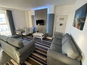 A modern living room with a flat-screen TV mounted on a wall, a striped rug, and two grey sofas. - Harbour View Apt, Oceana (East Riding of Yorkshire)