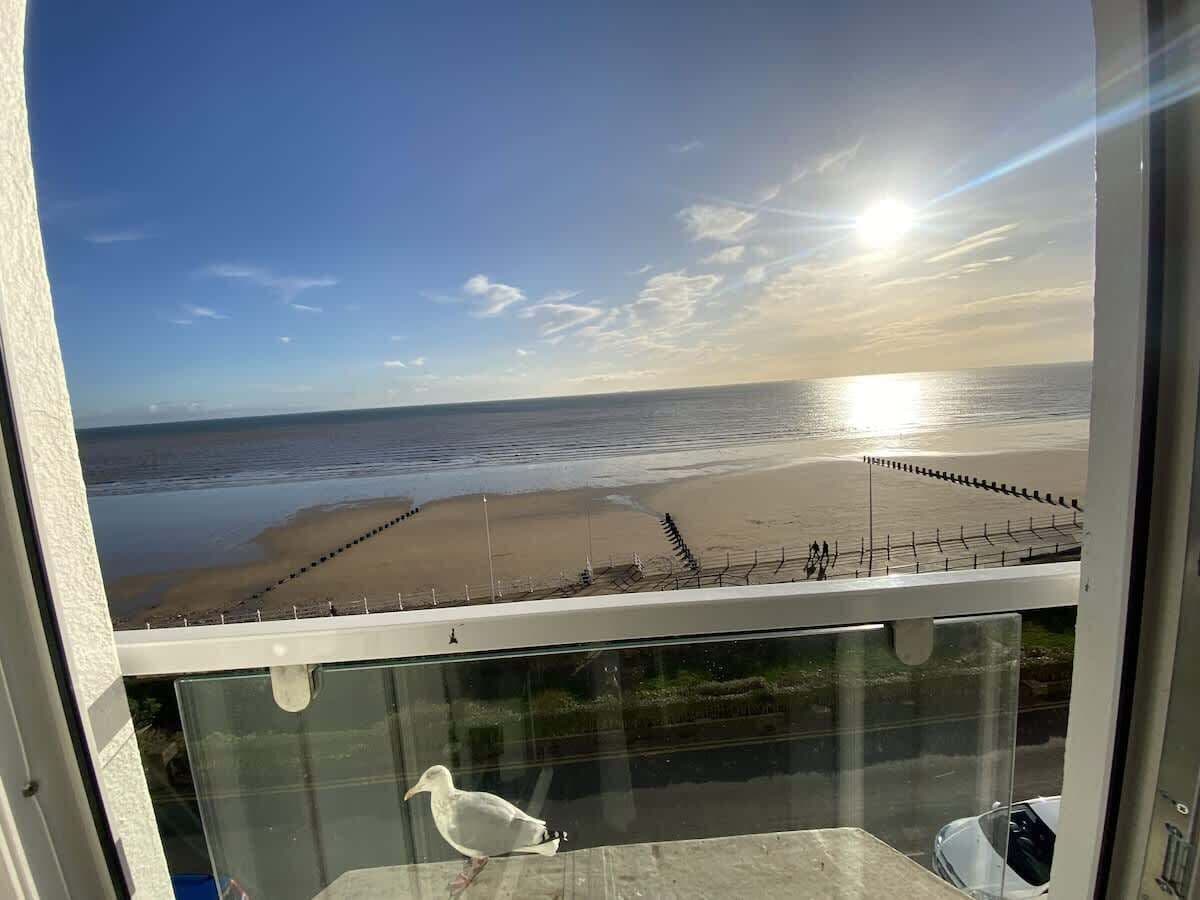 A view from a balcony overlooking a beach with a clear sky and the sun low on the horizon.