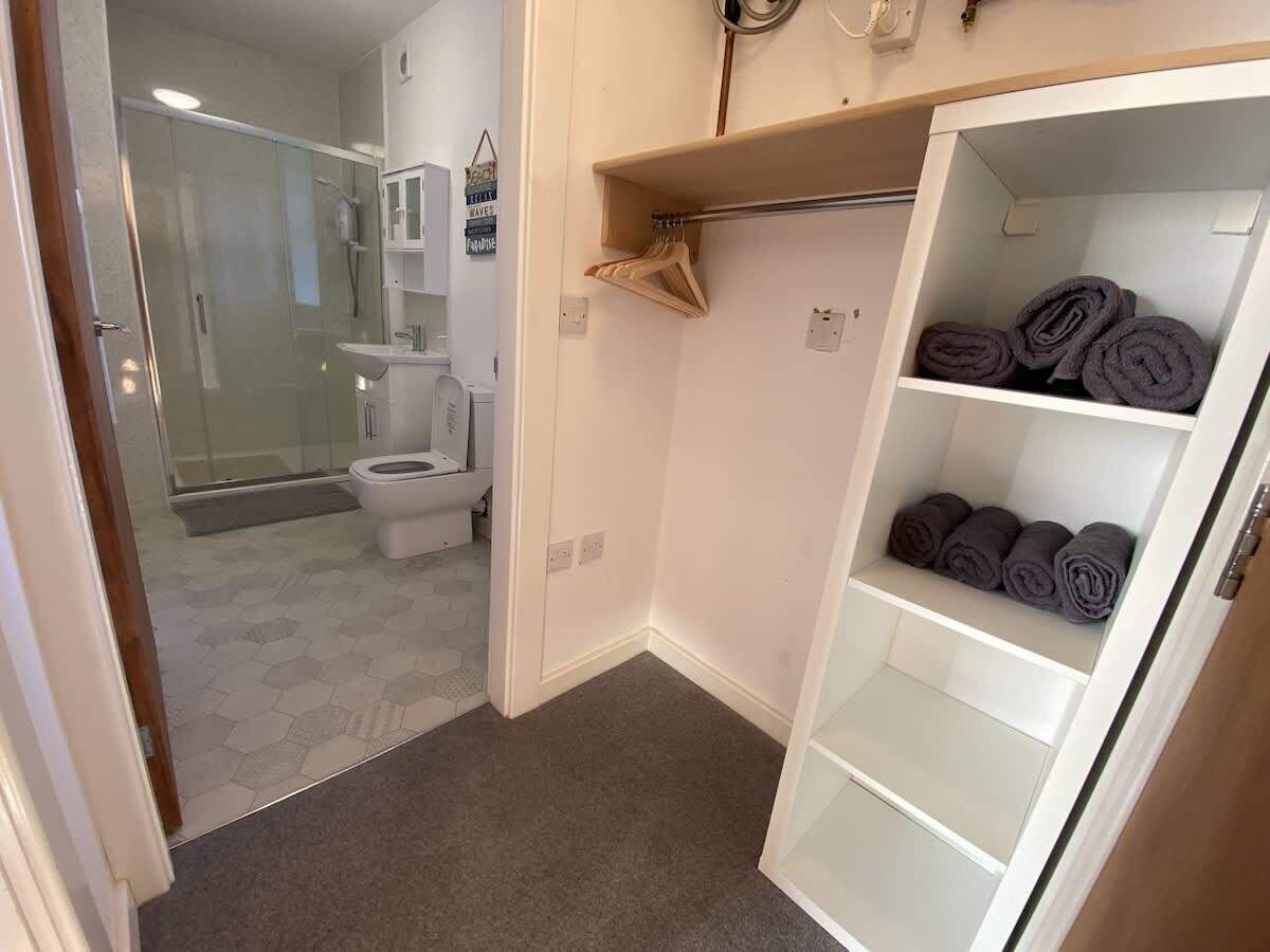 A bathroom with a glass shower enclosure, a toilet, and a towel rack.