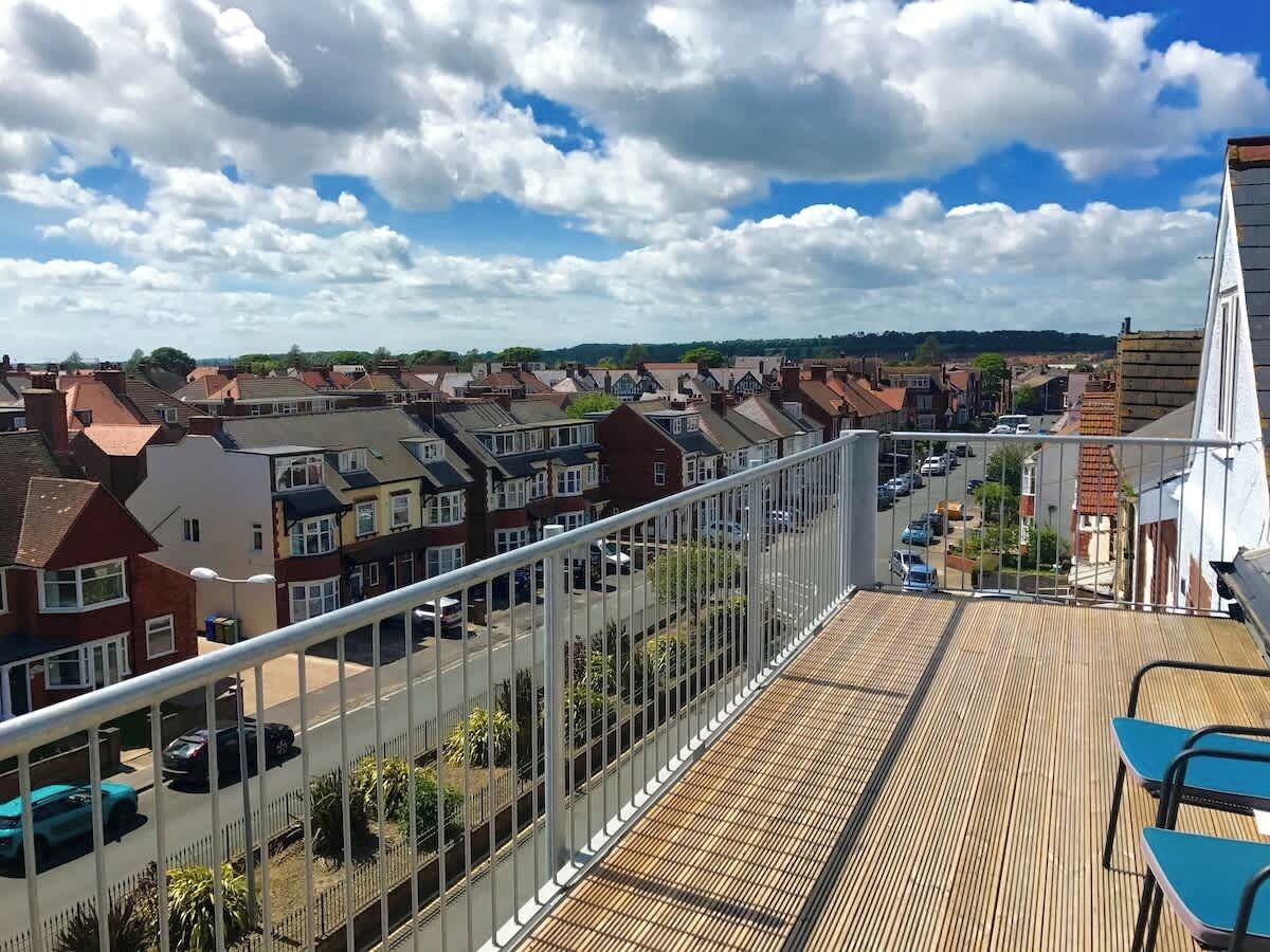 Un balcón con vistas a una zona residencial, que incluye casas y coches aparcados.