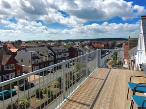 Un balcón con vistas a una zona residencial, que incluye casas y coches aparcados.
