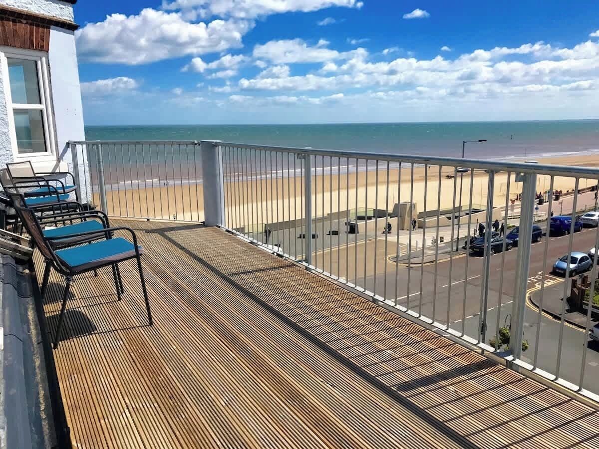 A balcony with a view of the beach and a parking area.