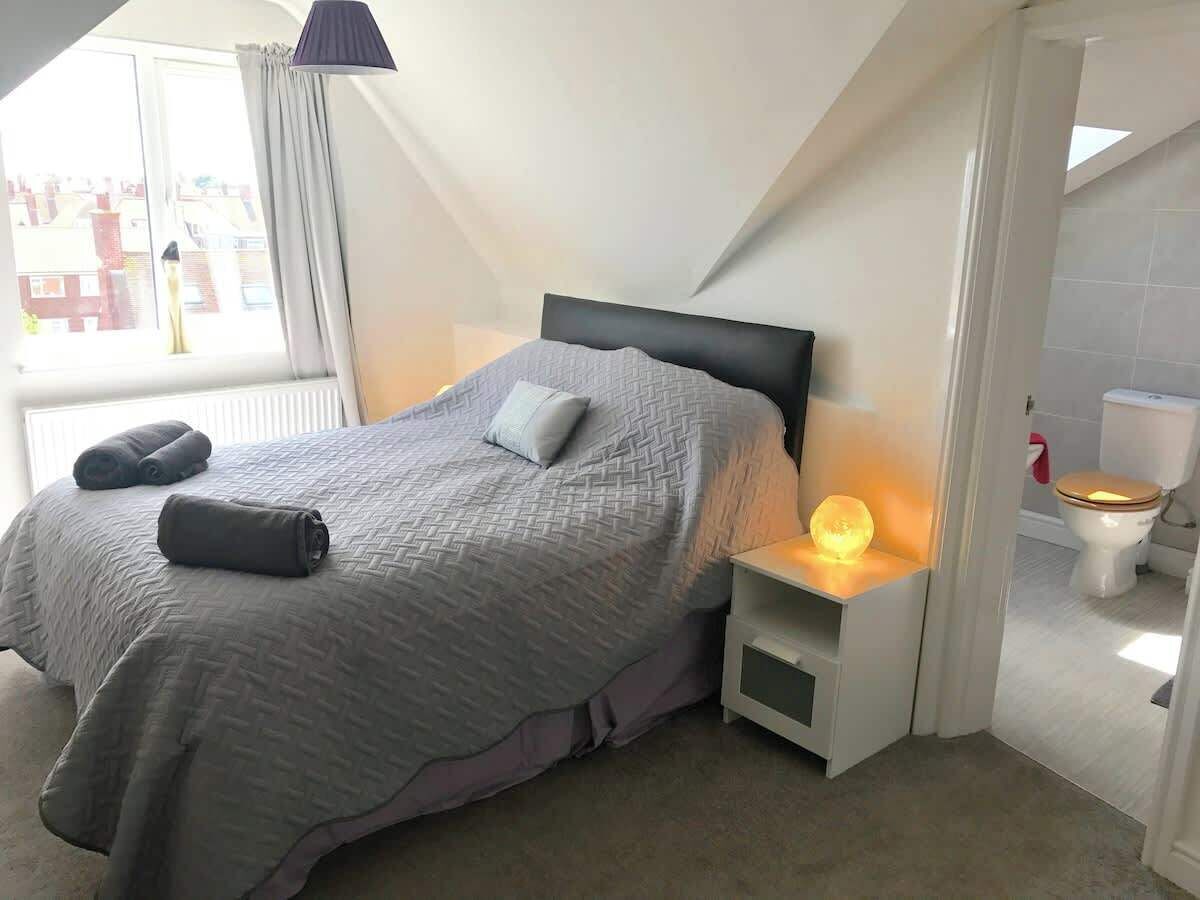A bedroom with a bed, bedside lamps, and a view of the outside.