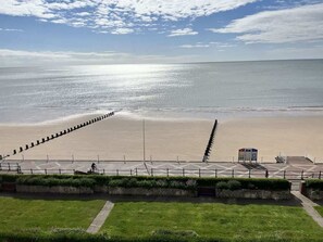 Une promenade en bord de mer avec un sentier, une plage et un ciel dégagé.