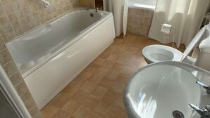 A bathroom with a bathtub, a toilet, and a sink. - Promenade Apt. Oceana (East Riding of Yorkshire)