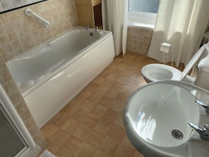A bathroom with a bathtub, a toilet, and a sink. - Promenade Apt. Oceana (East Riding of Yorkshire)