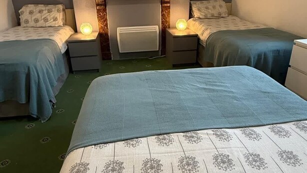 A hotel room with two single beds, a large bed, a mirror, and a wall-mounted artwork. - Promenade Apt. Oceana (East Riding of Yorkshire)
