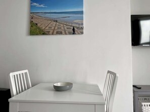 A dining area with a table, chairs, and a bowl. A television is mounted on the wall. - Balcony sea view apt for couples (East Riding of Yorkshire)