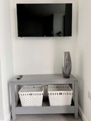 A grey console table with two white baskets and a vase. A remote control is on the table. - Balcony sea view apt for couples (East Riding of Yorkshire)