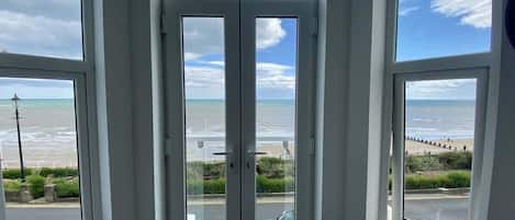 A view through a window with a beach and sea in the background.