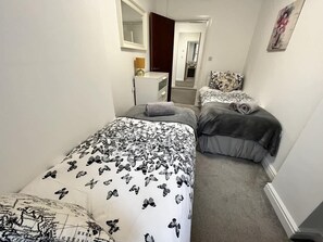A bedroom with two beds, a dresser, a mirror, and a door leading to another room. - 2 Bedroom Sea View Apartment with Balcony (Bridlington)