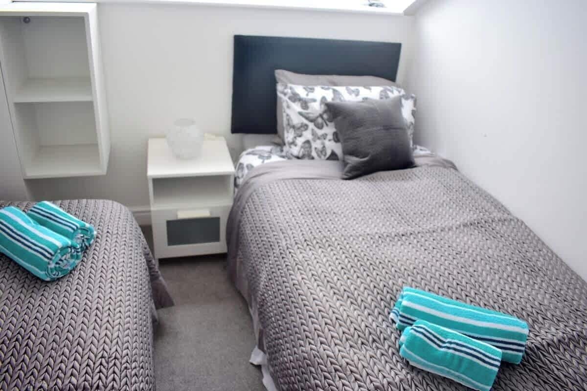 Een slaapkamer met twee bedden, een nachtkastje en een klein wit schap.