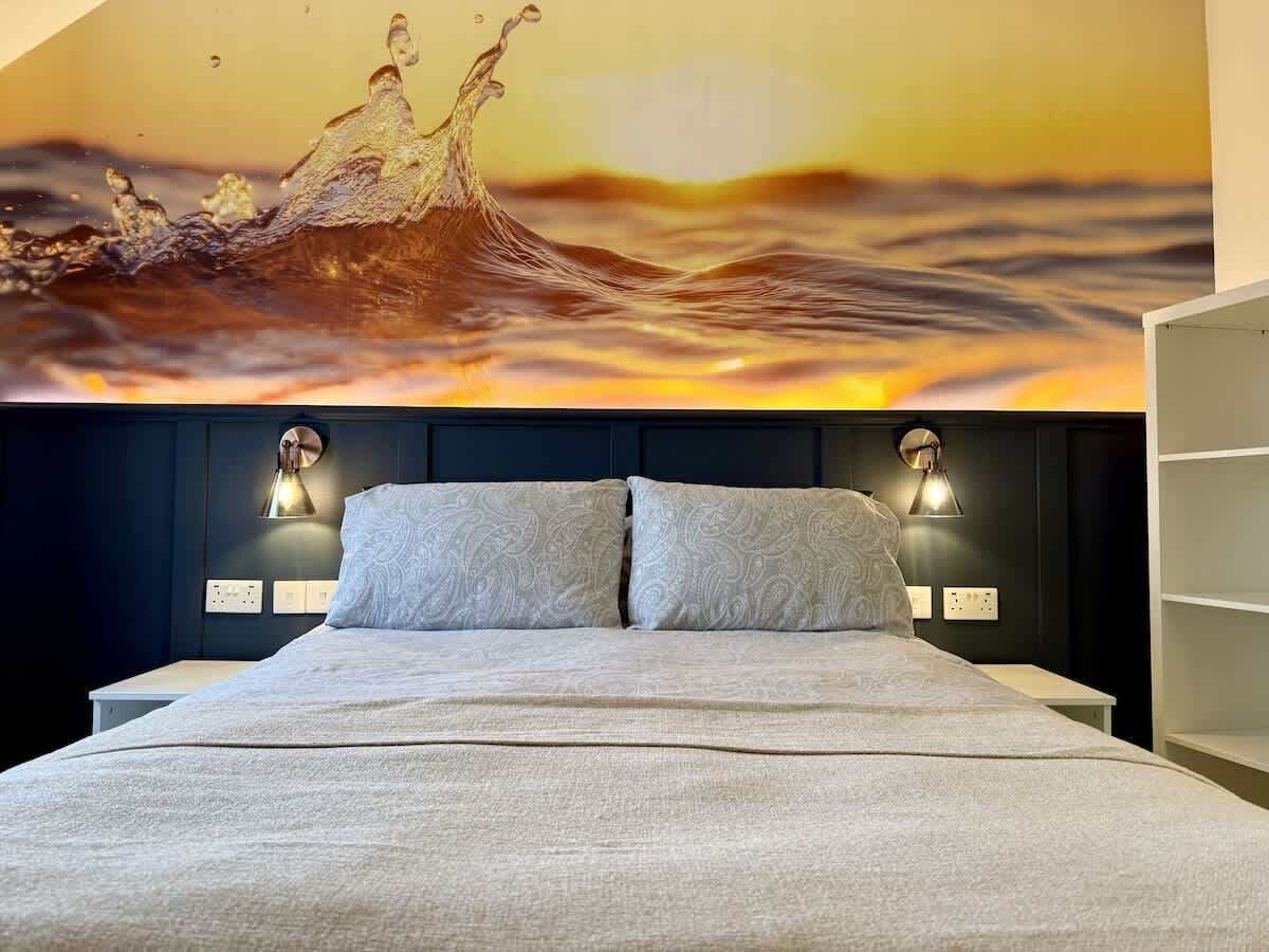 Un letto con testiera, due lampade da comodino e un murale.
