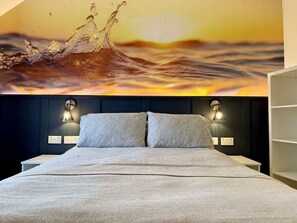Ein Bett mit Kopfteil, zwei Nachttischlampen und einer Wandmalerei.
