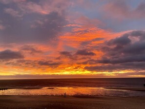 En strand med en solnedgång och en person som står på sanden.