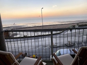 Ein Balkon mit Blick auf Strand und Meer bei Sonnenuntergang.