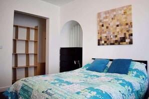 A bedroom with a bed, a wardrobe, a shelf unit, and a wall art piece. - Luxury 3 bedroom, sea view apartment with balcony (East Riding of Yorkshire)