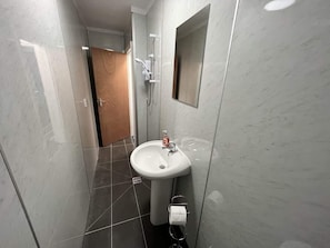 A bathroom with a white sink, a mirror, and a shower. - Ocean Wave Apt. Oceana (East Riding of Yorkshire)