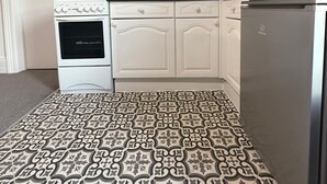 A kitchen with white cabinets, a stove, a microwave, and a refrigerator. - Ocean Wave Apt. Oceana (East Riding of Yorkshire)