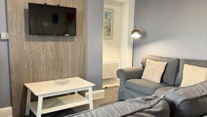A living room with a grey sofa, a white coffee table, and a mounted TV. - Ocean Wave Apt. Oceana (East Riding of Yorkshire)