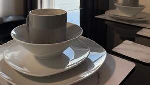 A kitchen with a view of the sea through a window, a microwave, and a set of white plates and cups. - Ocean Wave Apt. Oceana (East Riding of Yorkshire)