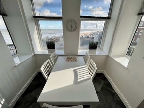 A conference room with a white table, white chairs, a clock on the wall, and large windows with a view of the sea and buildings. - Large luxury property, sea view (East Riding of Yorkshire)