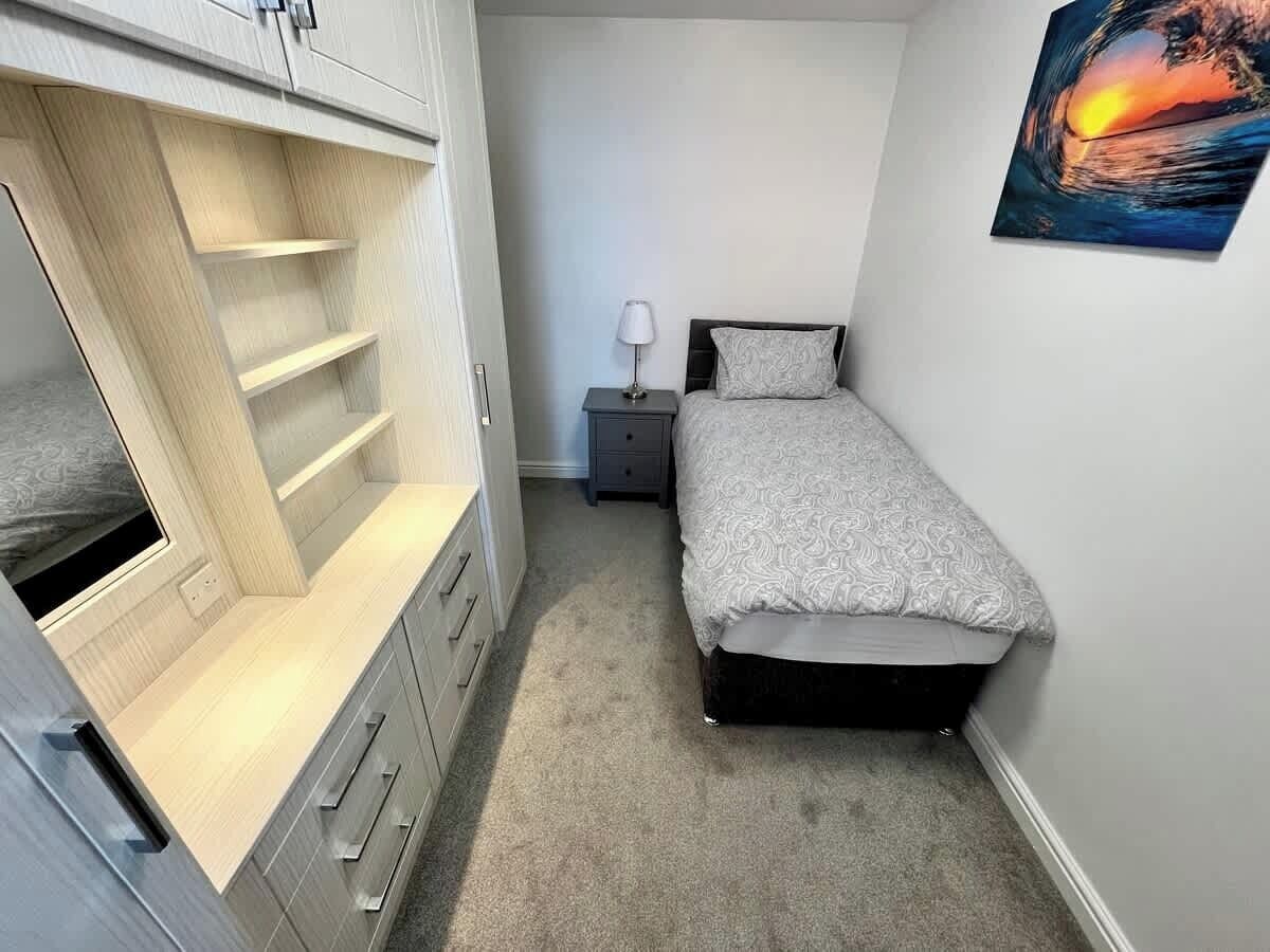 Une chambre à coucher avec un lit, une table de chevet, une lampe et un tableau accroché au mur.