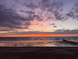 A beach with a wooden jetty extending into the water, a clear sky, and a sunset. - Seaside Escapes Apt. 2 (East Riding of Yorkshire)
