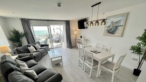 A modern living room with a sofa set, dining table, and chairs. - Seaside Escapes Apt. 2 (East Riding of Yorkshire)