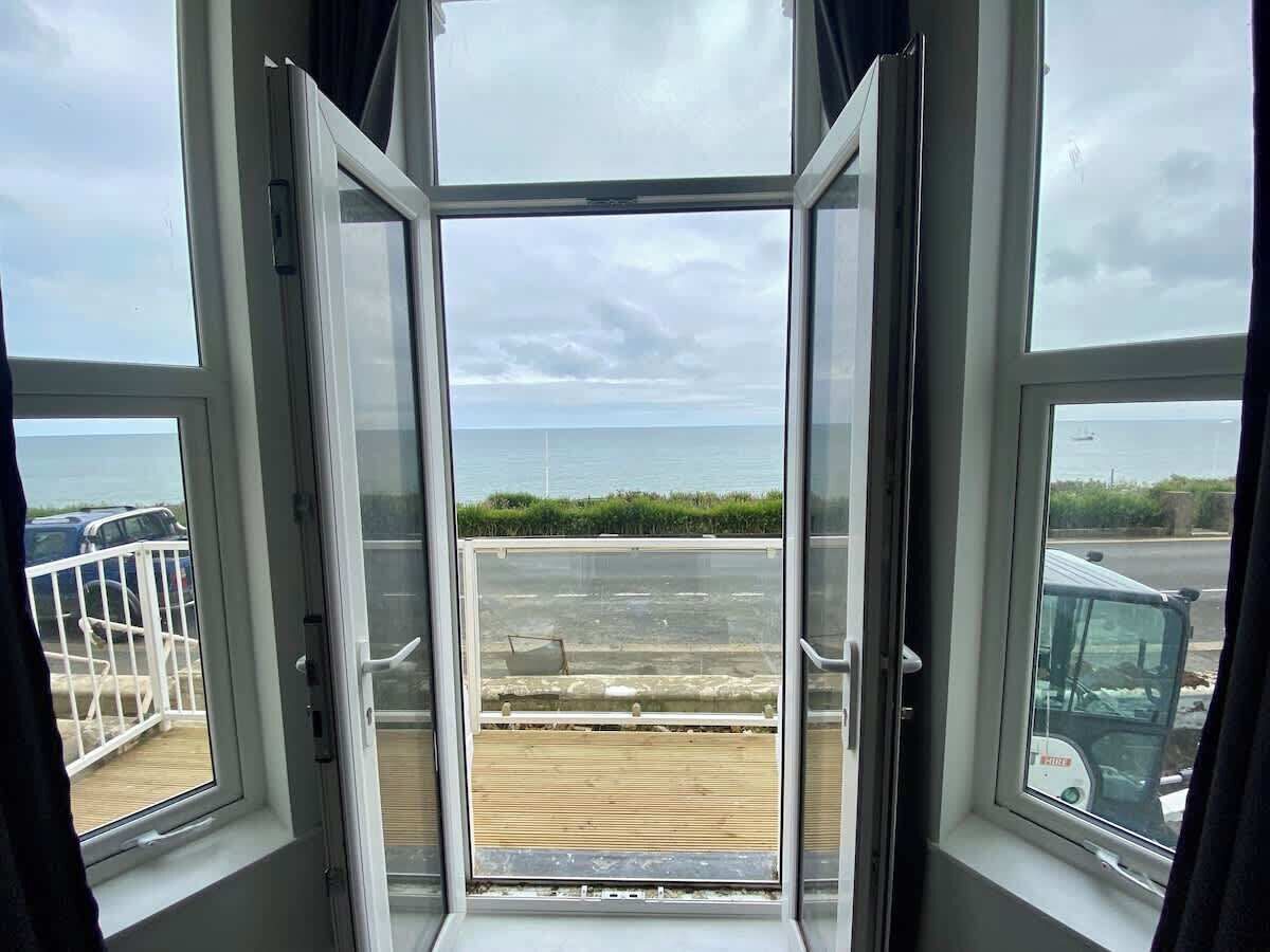 Ein offenes Fenster mit Blick auf einen Strand und einen Parkplatz.
