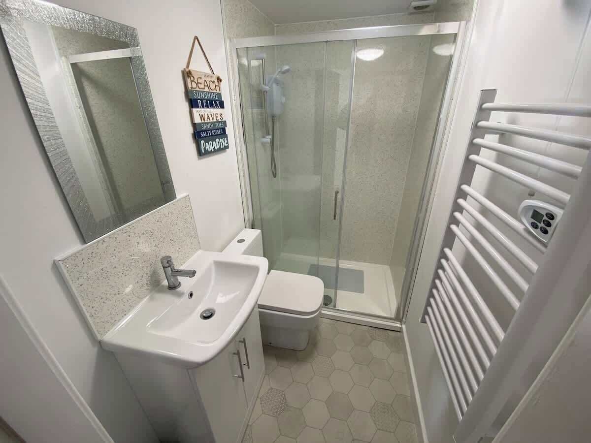Et badeværelse med vask, toilet og brusekabine i glas.