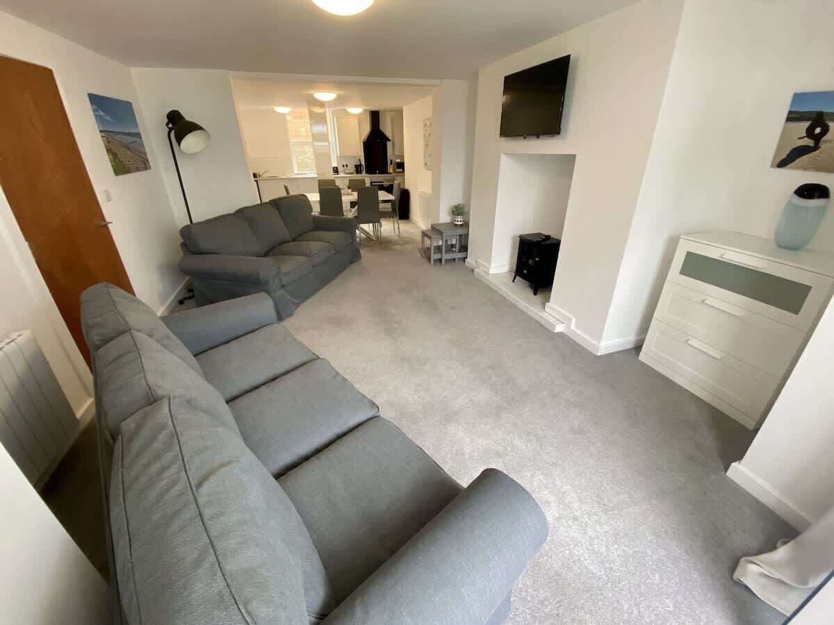 A living room with a grey sectional sofa, a fireplace, and a TV mounted on the wall.