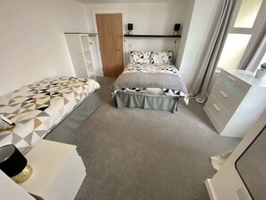 A bedroom with two beds, a wardrobe, a desk, and a mirror. - Bridlington Bay Apt.1 (East Riding of Yorkshire)