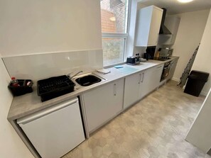 Eine kompakte Küche mit Spüle, Herd und Schränken, mit einem Fenster und einem gemusterten Boden.