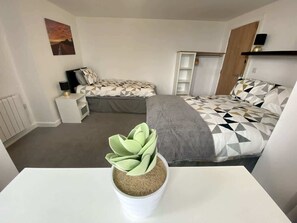 Ein Schlafzimmer mit einem Bett, Nachttischen, einer Wandablage und einem Blumentopf.