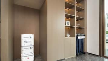A hotel room with a built-in wardrobe, a minibar, and a window with curtains.
