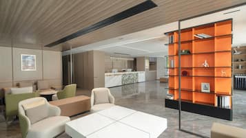 A modern interior with a reception desk, seating area, and a bookshelf.
