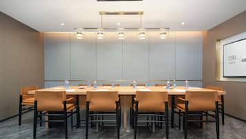 A conference room with a long table, chairs, and a projector screen.