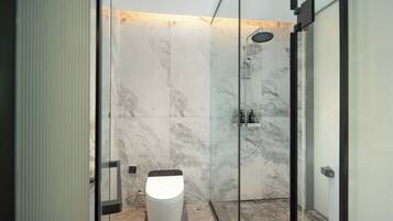 Une salle de bain moderne avec une douche à parois de verre, des murs en marbre et des toilettes.