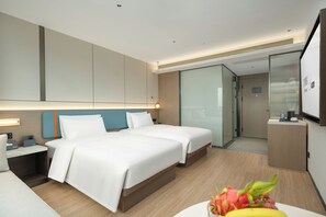 Una habitación de hotel moderna con una cama grande, mesitas de noche, un escritorio y un espejo.