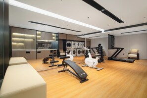 Un gimnasio moderno con diversos equipos de ejercicio, una banca y una cinta de correr.