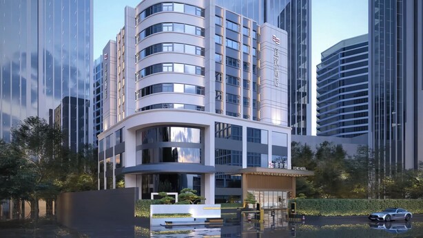 Un hotel moderno con fachada curva, varios pisos y una entrada central con porche cubierto.