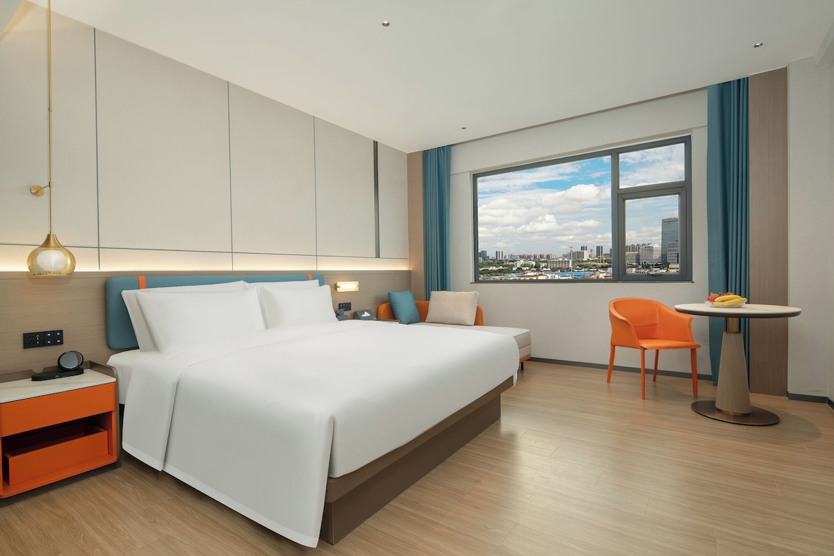 Una camera d'albergo con un letto, un comodino, una sedia e una finestra vista città.