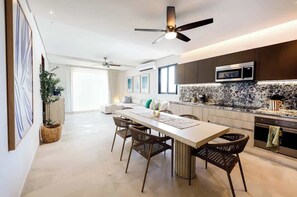 A modern kitchen with a microwave, a dining area with a table and chairs, and a ceiling fan. - Apt Jaribu: Ocean Views & Shared Pool (Puerto Morelos)
