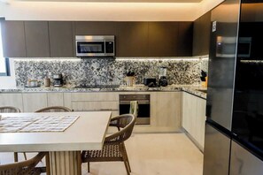 A modern kitchen with a built-in microwave, oven, and refrigerator. - Apt Jaribu: Ocean Views & Shared Pool (Puerto Morelos)