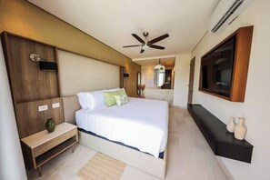 A bedroom with a bed, bedside table, and a TV mounted on the wall. - Apt Huico: Ocean Views, Shared Rooftop & Pool (Puerto Morelos)