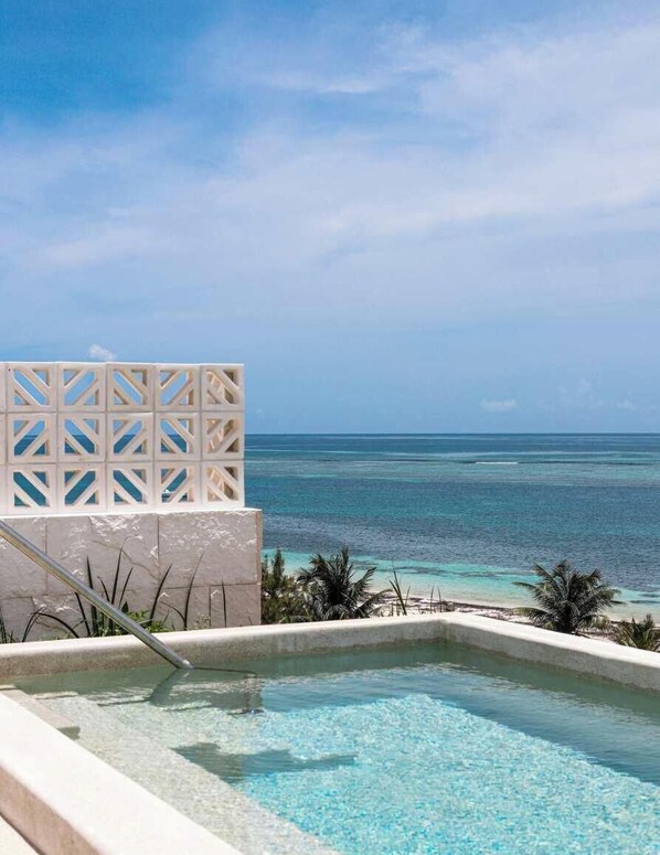 A pool with a clear view of the ocean and a white structure with a lattice design. - Apt Huico: Ocean Views, Shared Rooftop & Pool (Puerto Morelos)