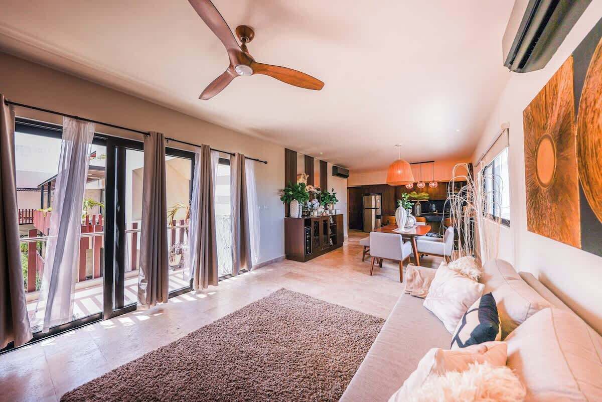 A spacious living area with a sofa, a dining table, and a ceiling fan.