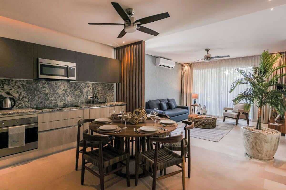 Eine moderne Küche mit Essbereich, ein Wohnzimmer mit einer Couch und einem Deckenventilator.