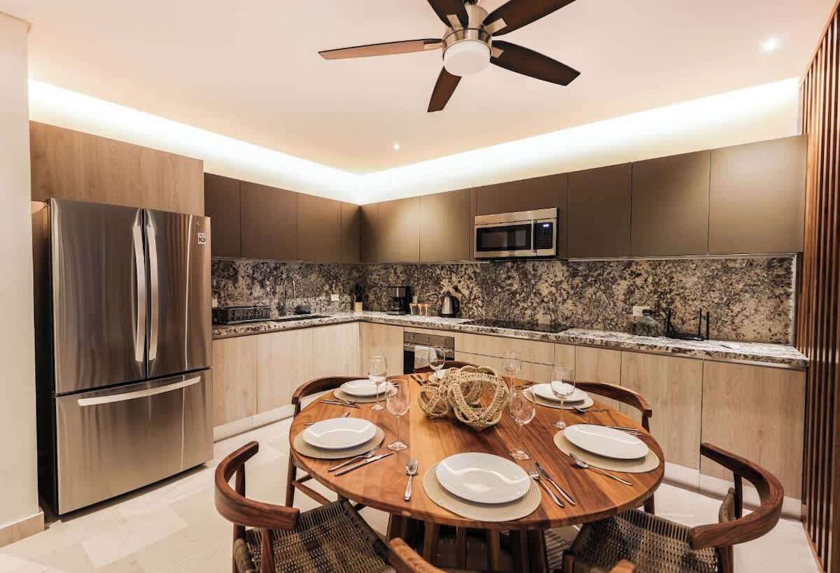 A modern kitchen with a built-in microwave, stainless steel refrigerator, and a round dining table set for four.